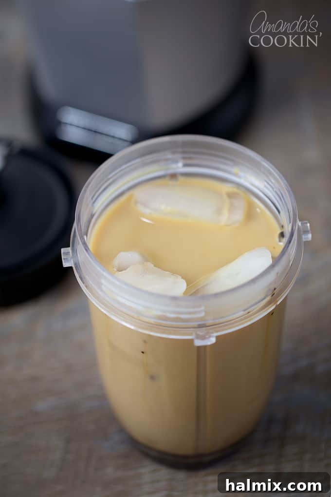 Homemade Mocha Frappe Magic 6 Adding ice to the blender, ensuring the ice cubes rise above the liquid ingredients for a perfectly thick and slushy mocha frappuccino.