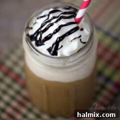 Homemade Mocha Frappe Magic 9 An overhead shot of a mason jar filled with a mocha Frappucino topped with whipped cream, chocolate sauce and a red and white stripped straw, showcasing a perfect homemade blend.