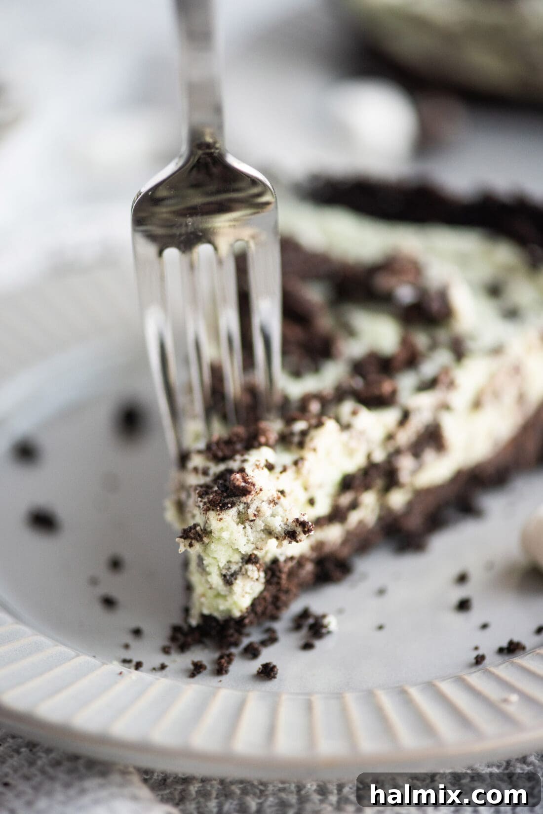 Emerald Mint Delight 2 Fork in a slice of creamy, minty green Grasshopper Pie with chocolate crust and Oreo crumble topping.