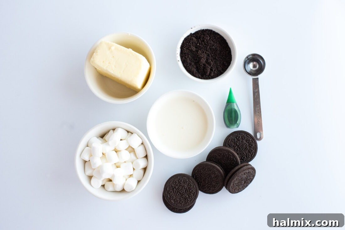 Emerald Mint Delight 4 A collection of the seven simple ingredients needed for a no-bake Grasshopper Pie recipe, including marshmallows, heavy cream, chocolate graham crackers, and peppermint extract.