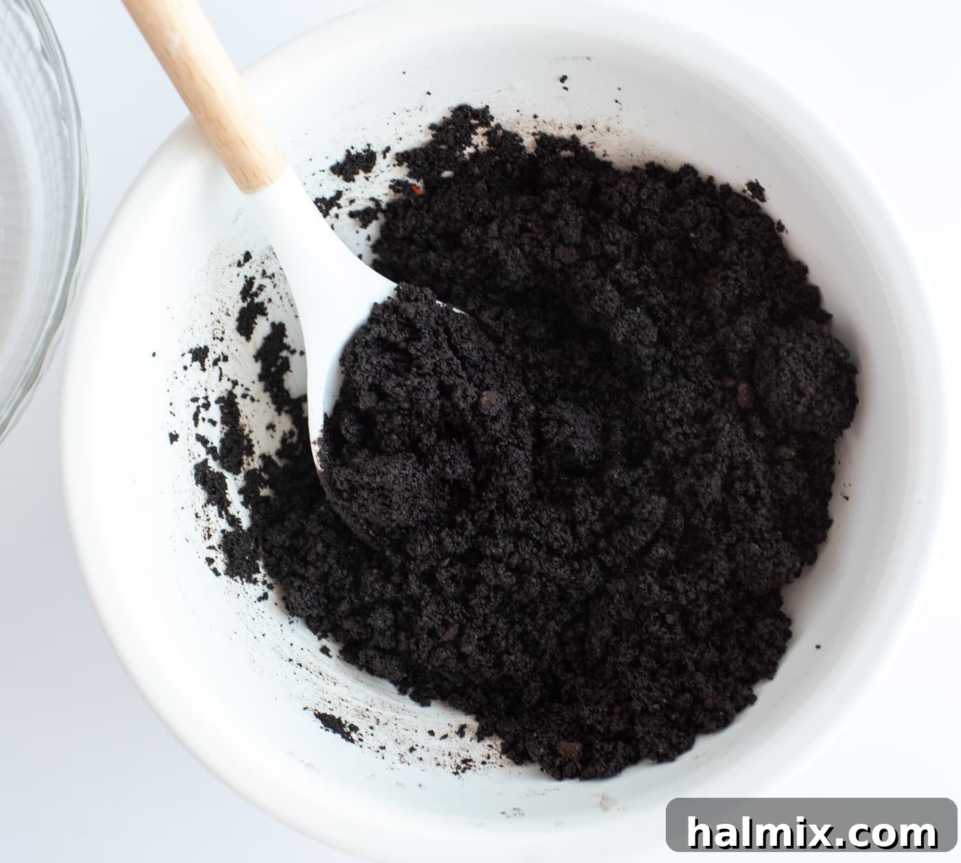 Emerald Mint Delight 5 Close-up of chocolate graham cracker crumbs being mixed with melted butter in a bowl.