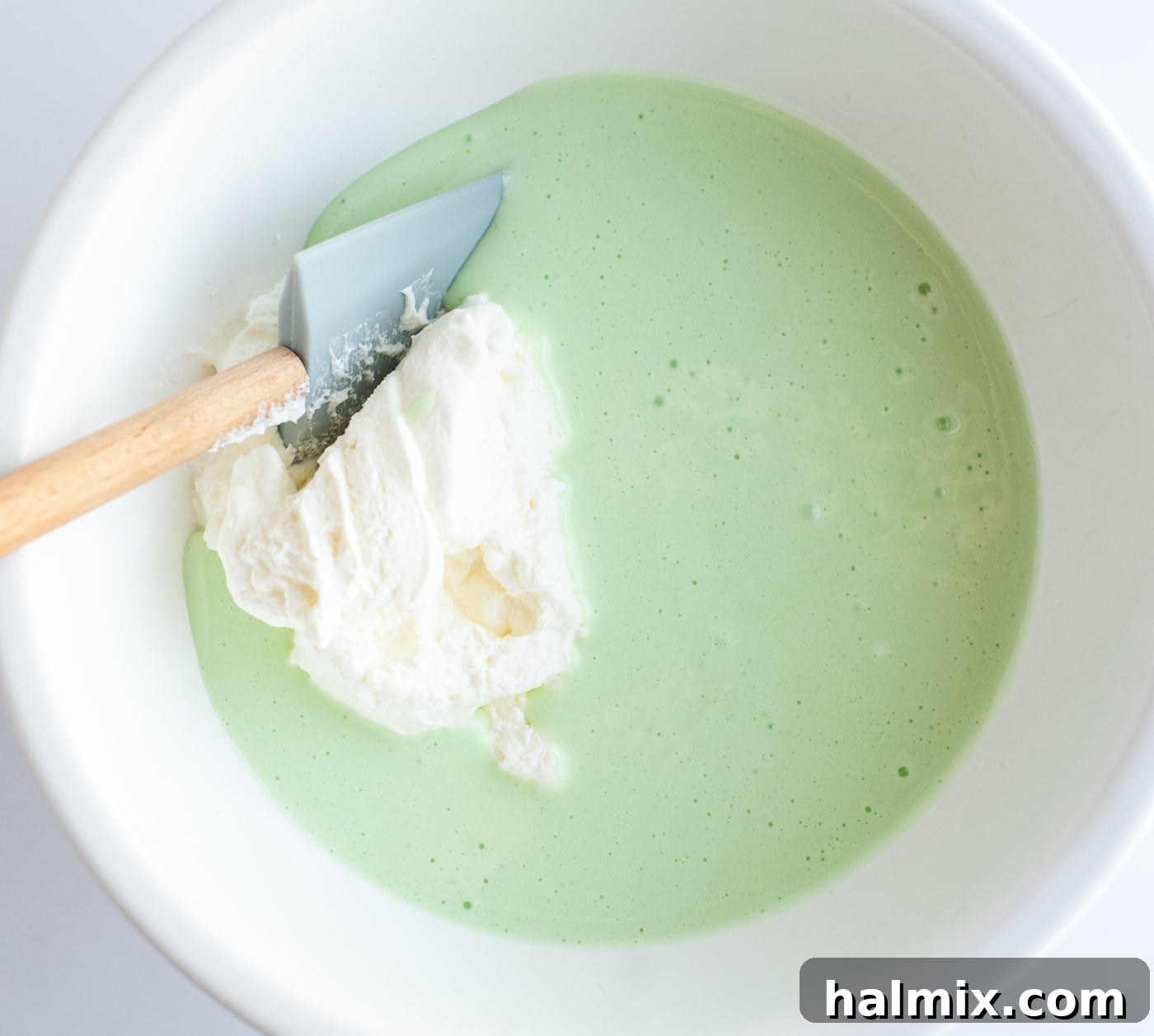 Emerald Mint Delight 8 Green food coloring and peppermint extract being stirred into the melted marshmallow and cream mixture.