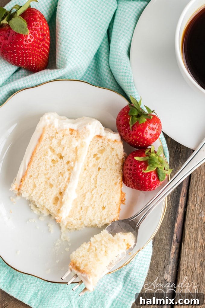Timeless Vanilla White Cake 2 slice of white cake on a plate with strawberries and a fork