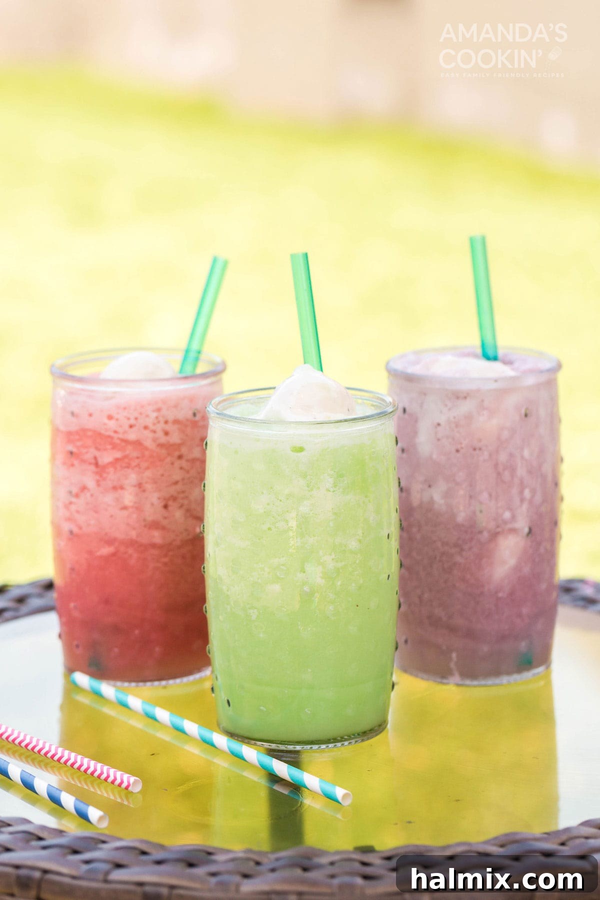 Three colorful homemade slushie floats, topped with ice cream, sitting on an outdoor table, inviting a cool summer sip.