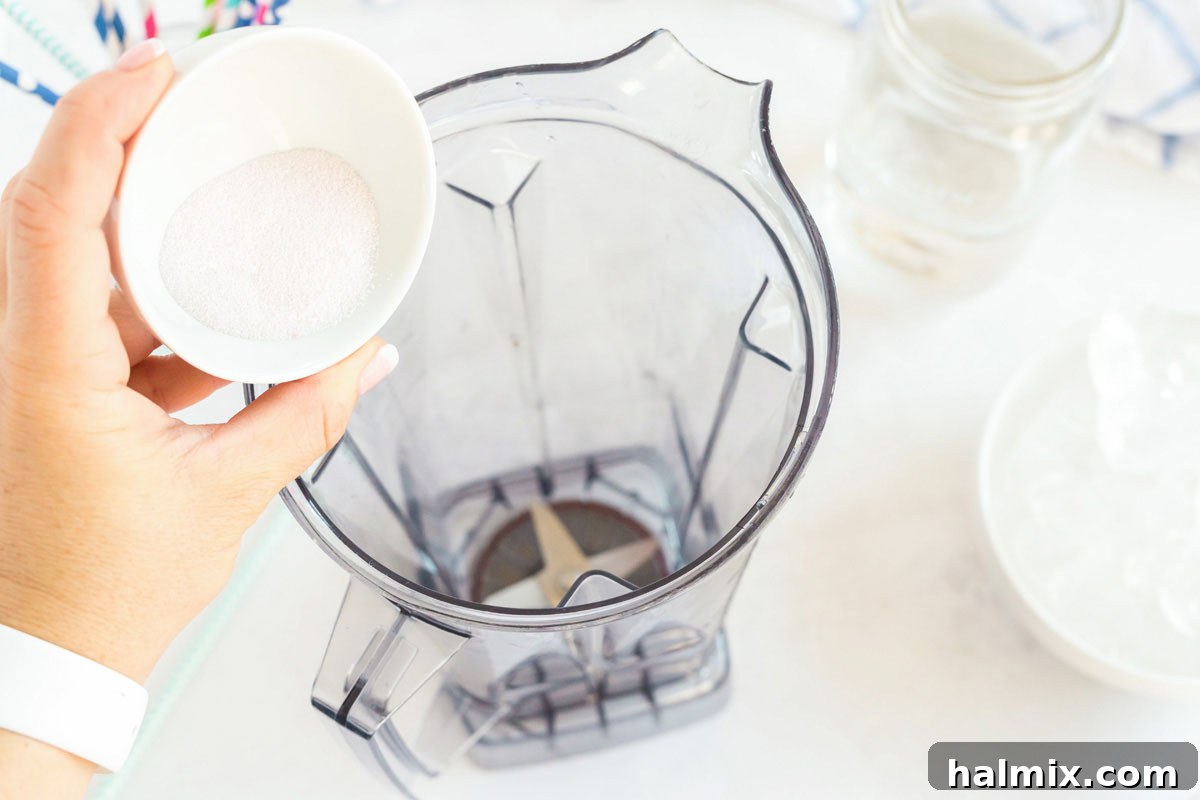 Pouring a packet of vibrant powdered drink mix into a blender, beginning the slushie creation process.