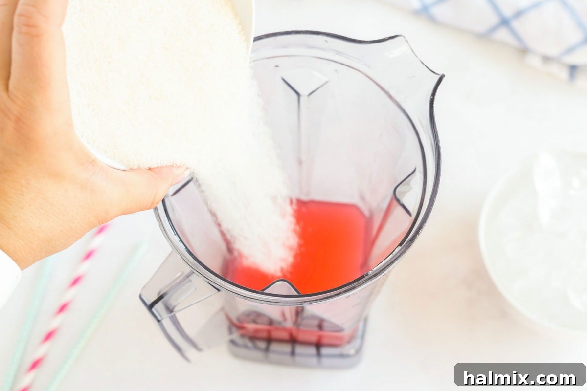 Sprinkling white granulated sugar into the blender, an essential ingredient for balancing the slushie's flavor.