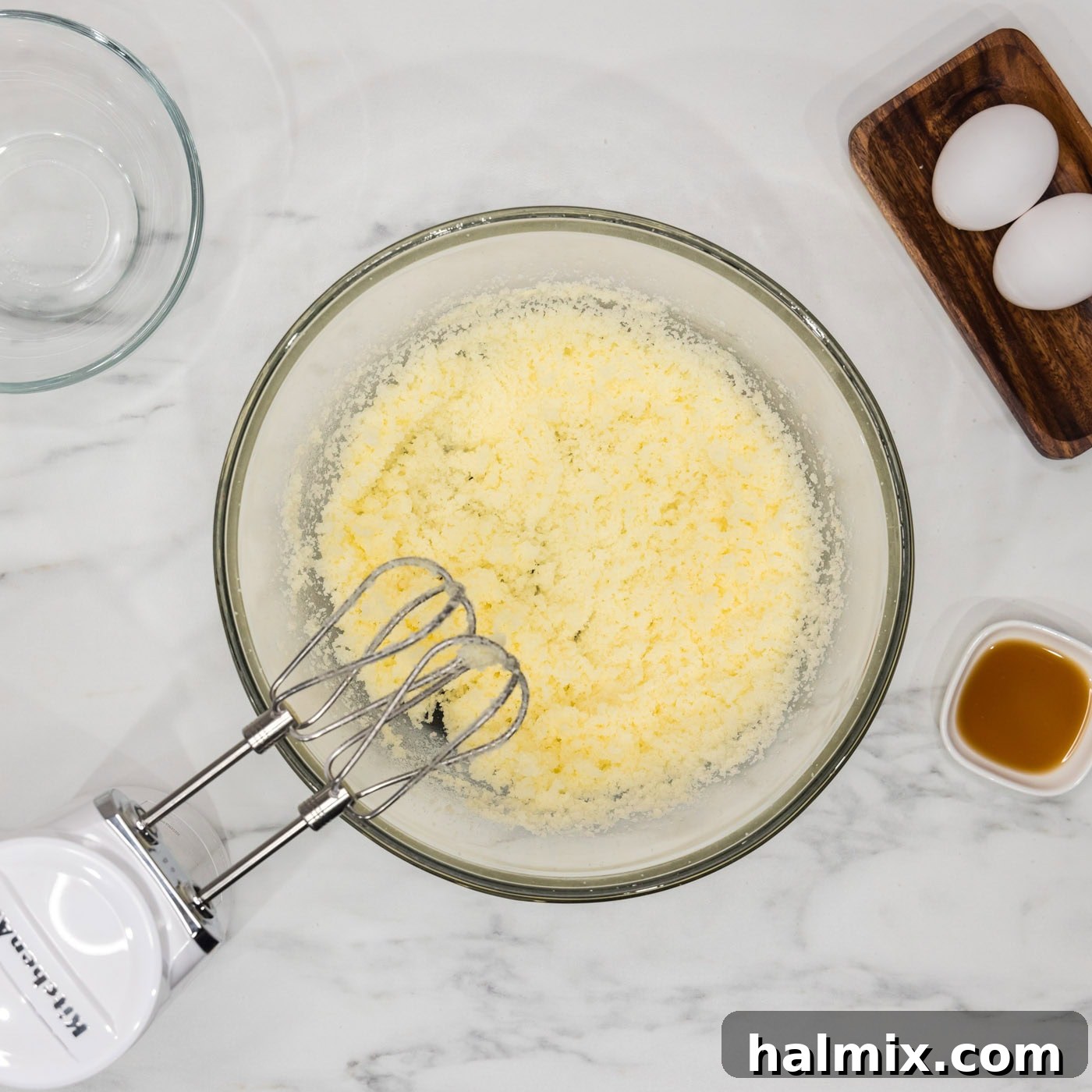 Shortening and sugar creamed together in a bowl with a hand mixer, looking light and fluffy.