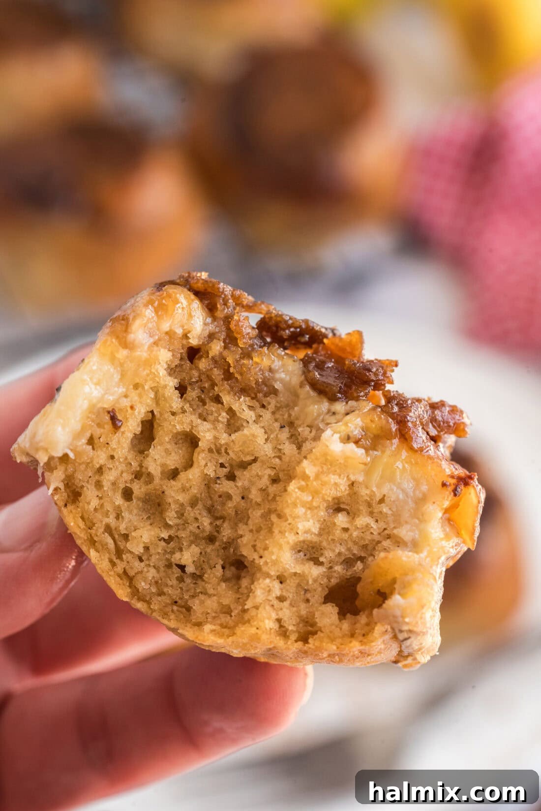 Hand holding up a Banana Upside Down Muffin with two bites taken out 