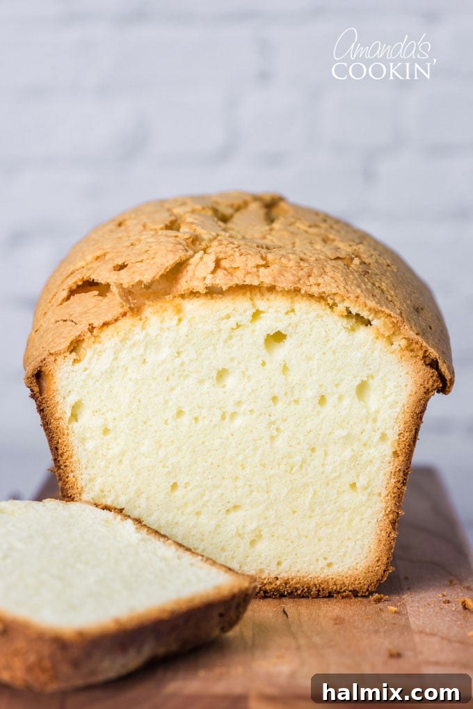 Classic Whipping Cream Pound Cake: Rich, Moist, and Irresistible A golden-brown whipping cream pound cake with a slice removed, revealing its moist interior, resting on a rustic wooden surface.