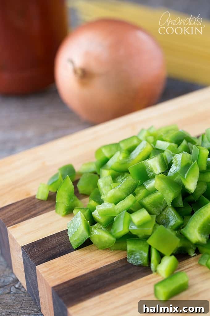 Golden Crust Spaghetti Pie 4 Freshly chopped green bell pepper on a wooden cutting board, ready for cooking.