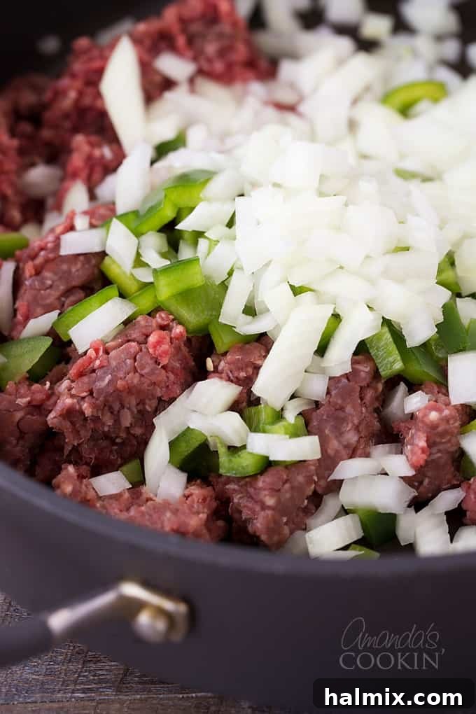 Golden Crust Spaghetti Pie 5 A close-up shot of ground beef, chopped green bell pepper, and chopped onion cooking together in a skillet.