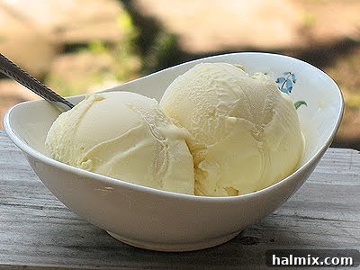 A close up of two scoops of white chocolate ice cream in a white bowl.