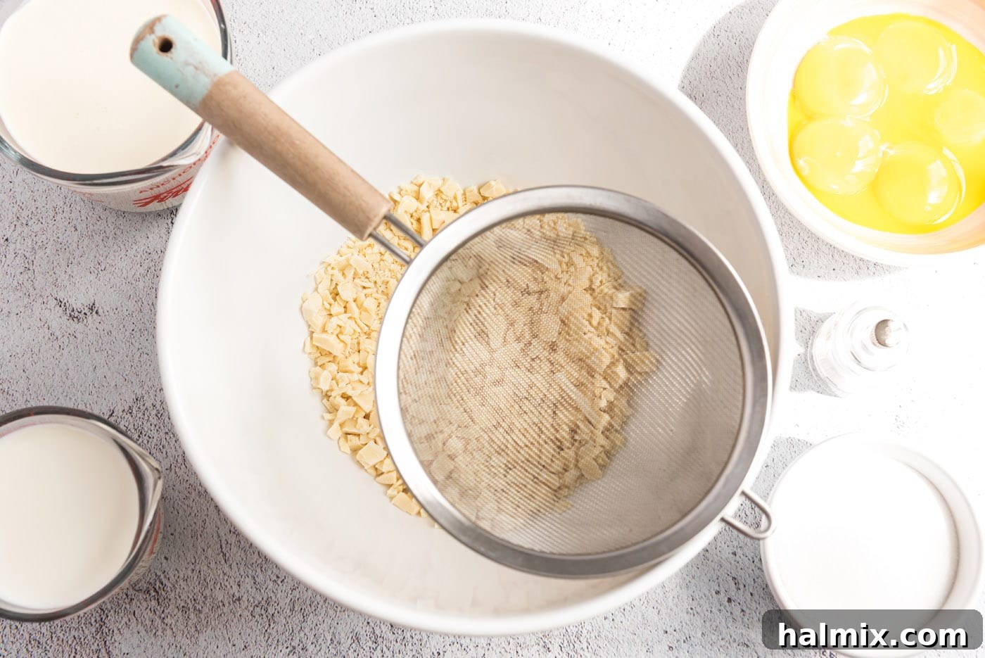 A photo of chopped white chocolate in a bowl and a mesh strainer over the top.