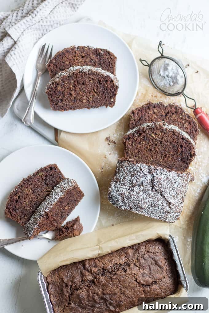 Moist Chocolate Zucchini Bread Recipe Sliced Chocolate Zucchini Bread dusted with powdered sugar, showcasing its moist texture and chocolate chips.