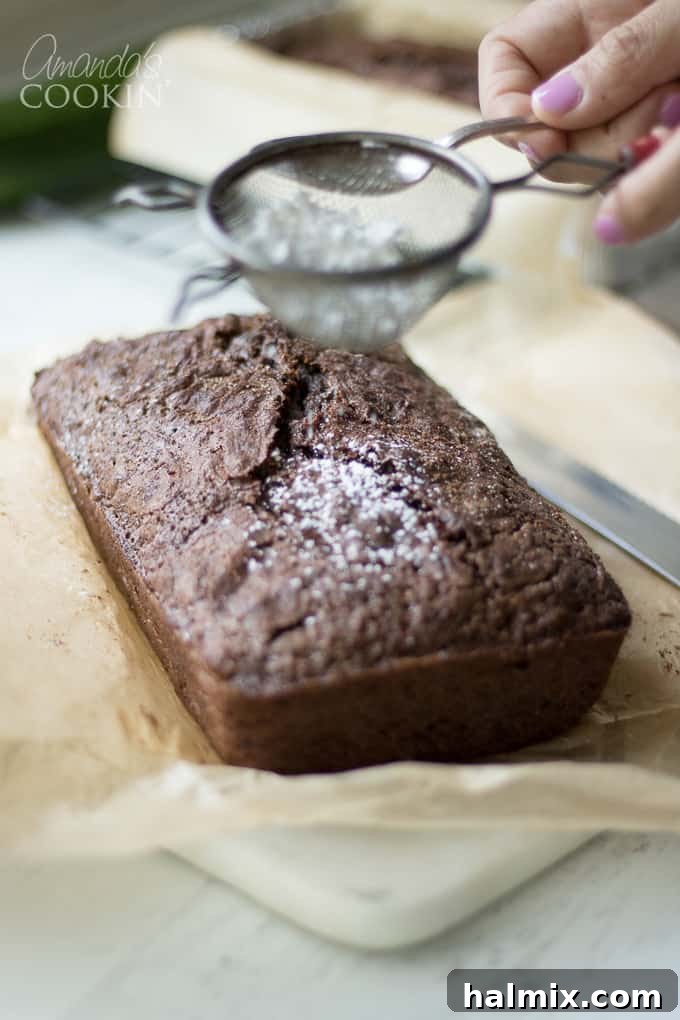 Secret Garden Chocolate Loaf 6 A baked loaf of chocolate zucchini bread being dusted with powdered sugar.