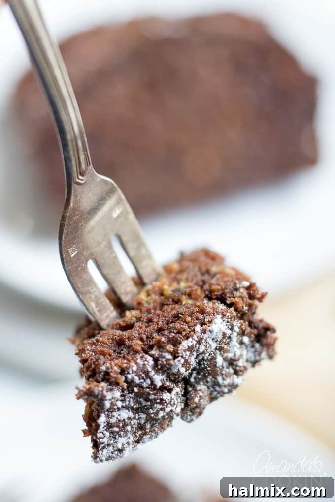 Enjoying Chocolate Zucchini Bread A fork taking a bite out of a slice of chocolate zucchini bread, highlighting its moist interior.