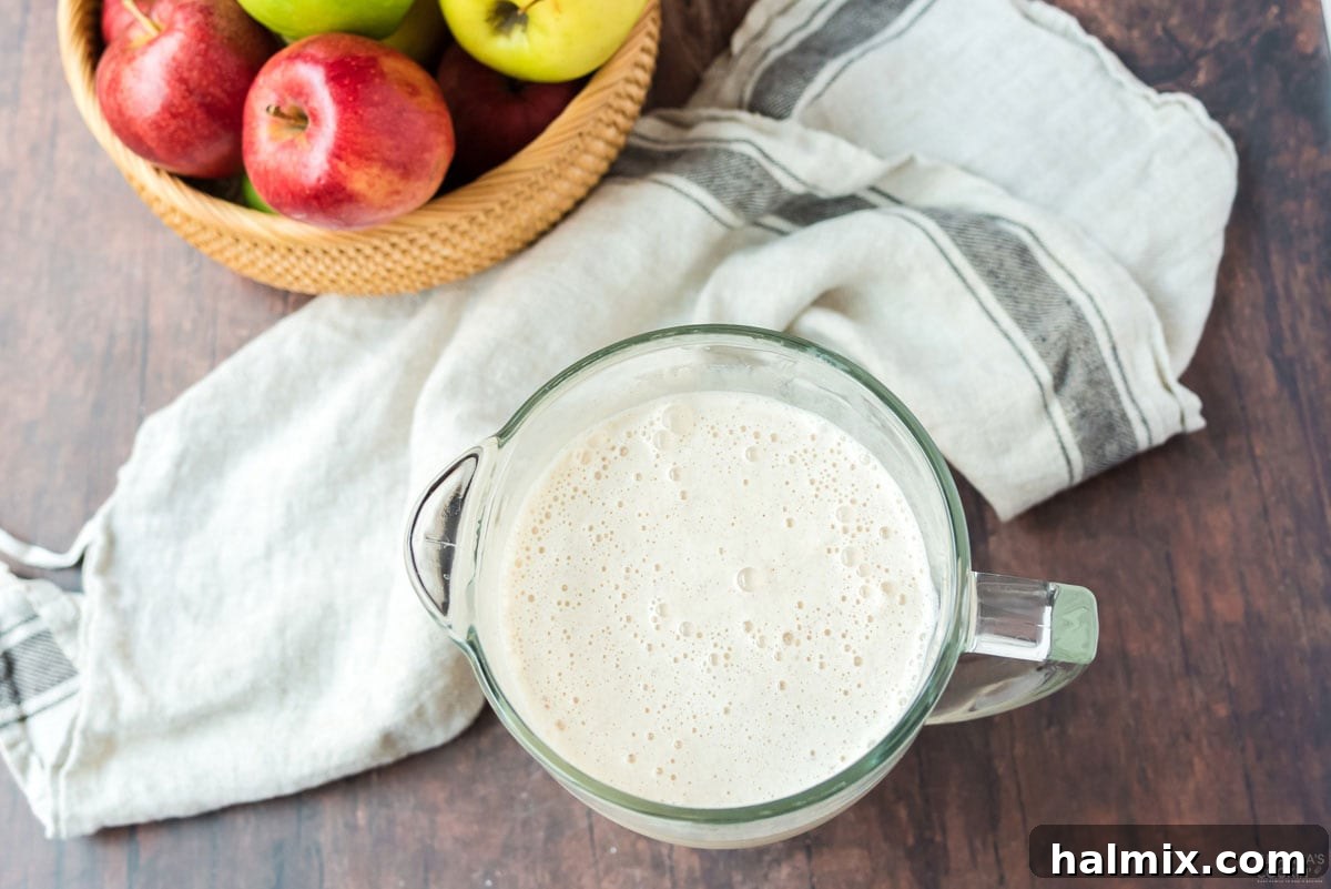 Spiced Apple Cream Shake 4 A measuring cup filled with a creamy, blended apple cider milkshake