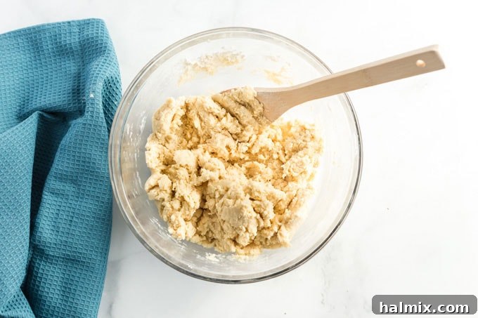 Cookie dough with dry ingredients being mixed in, starting to come together.