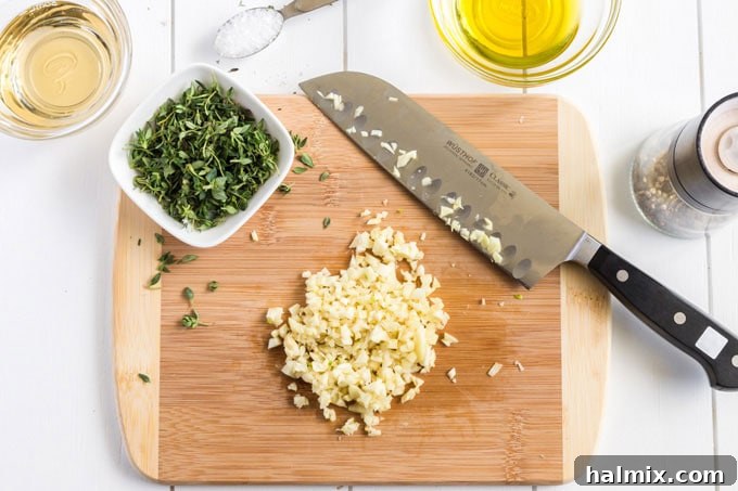 Freshly chopped garlic cloves and sprigs of fresh thyme on a cutting board, ready for the marinade.