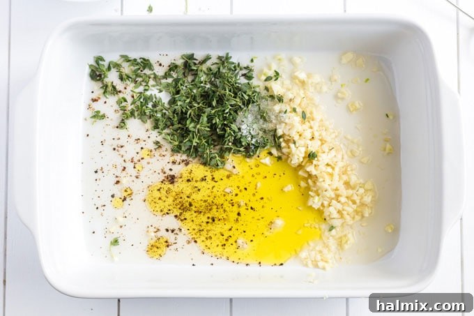 All the garlic marinade ingredients – olive oil, minced garlic, vinegar, thyme, salt, and pepper – perfectly combined in a baking dish.