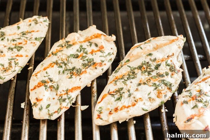 Perfectly seared garlic marinated chicken breasts cooking on an outdoor grill with visible grill marks.