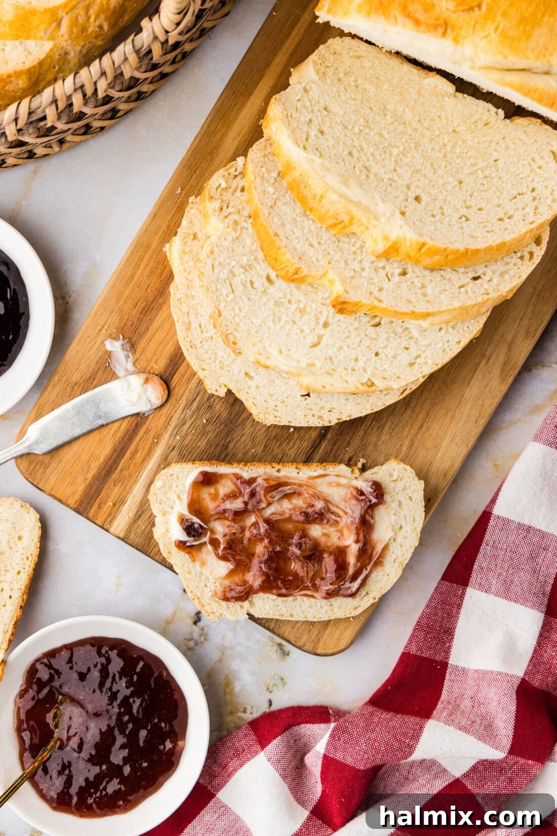 The 60-Minute Loaf 3 One Hour Bread sliced on a wooden cutting board, adorned with butter and jam, highlighting its soft texture