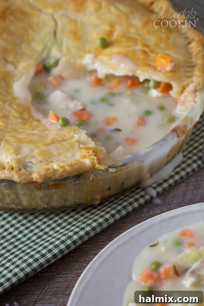 A close up of a homemade pot pie with a slice removed, revealing the rich, creamy interior.