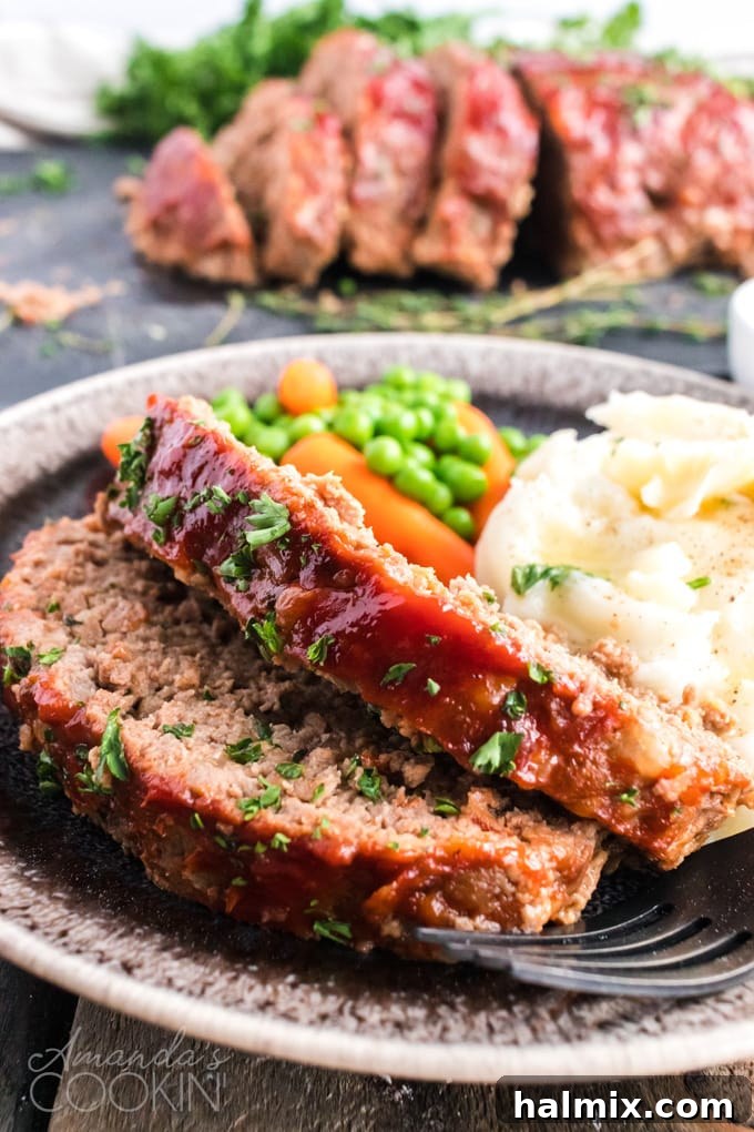 Two generous slices of glazed meatloaf served with creamy mashed potatoes on a white plate