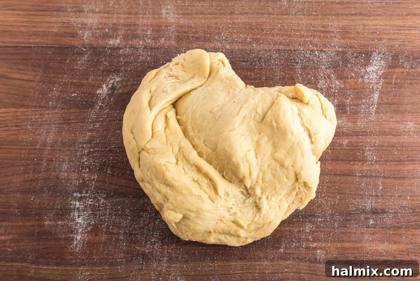 Hands kneading yeast dough on a cutting board, demonstrating the technique.
