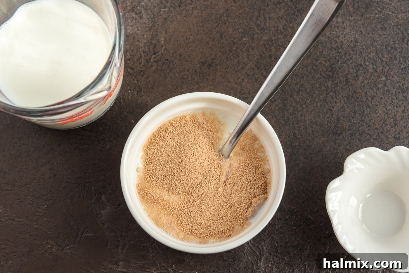 Mixing active dry yeast with lukewarm milk in a bowl, showing the initial activation step.