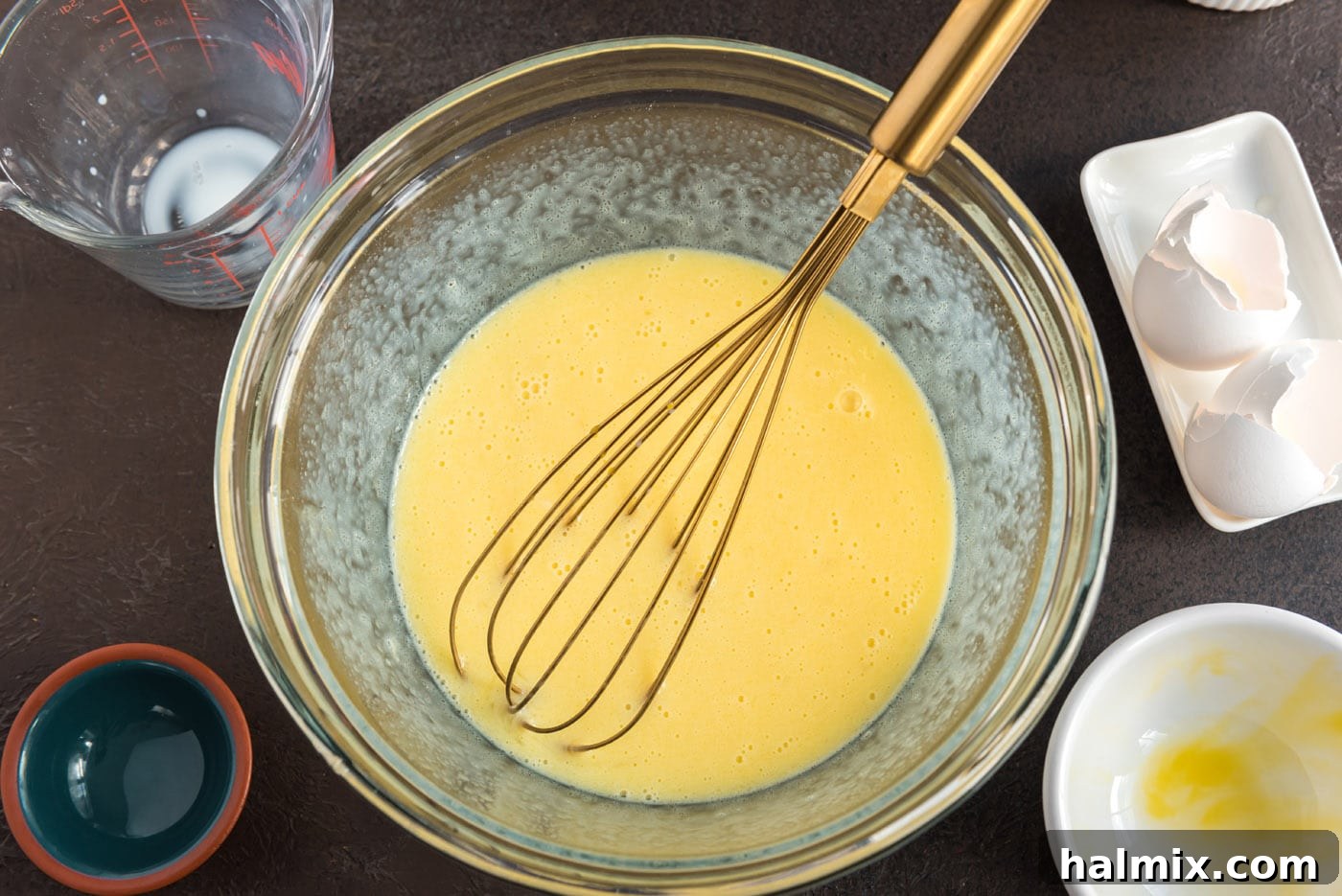 Whisked butter, milk, and egg mixture in a bowl, showing a uniform liquid consistency.