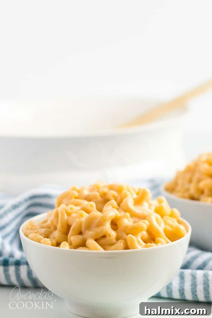 A hand pouring milk into a saucepan to create the cheese sauce for stovetop mac and cheese.