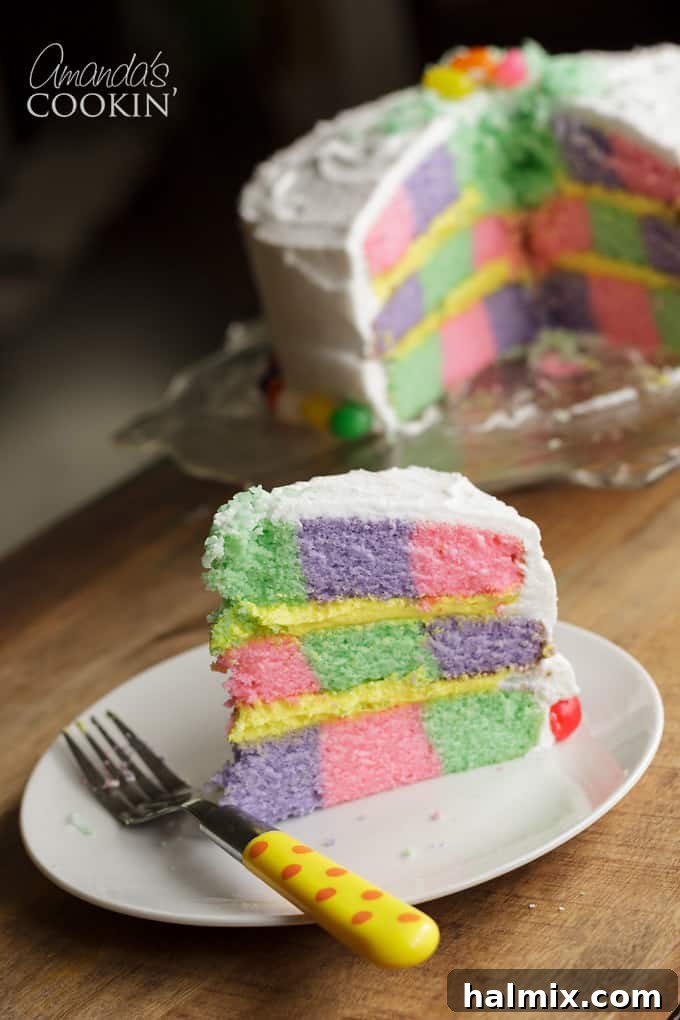 A slice of pastel checkerboard cake revealing the colorful pattern