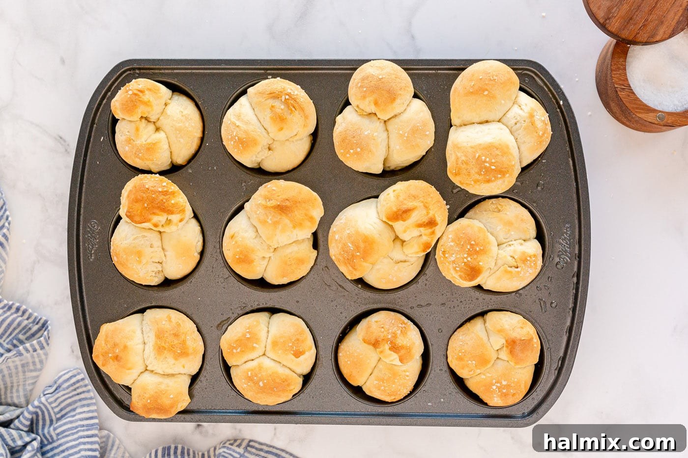 Golden brown homemade dinner rolls fresh out of the oven in a muffin pan.