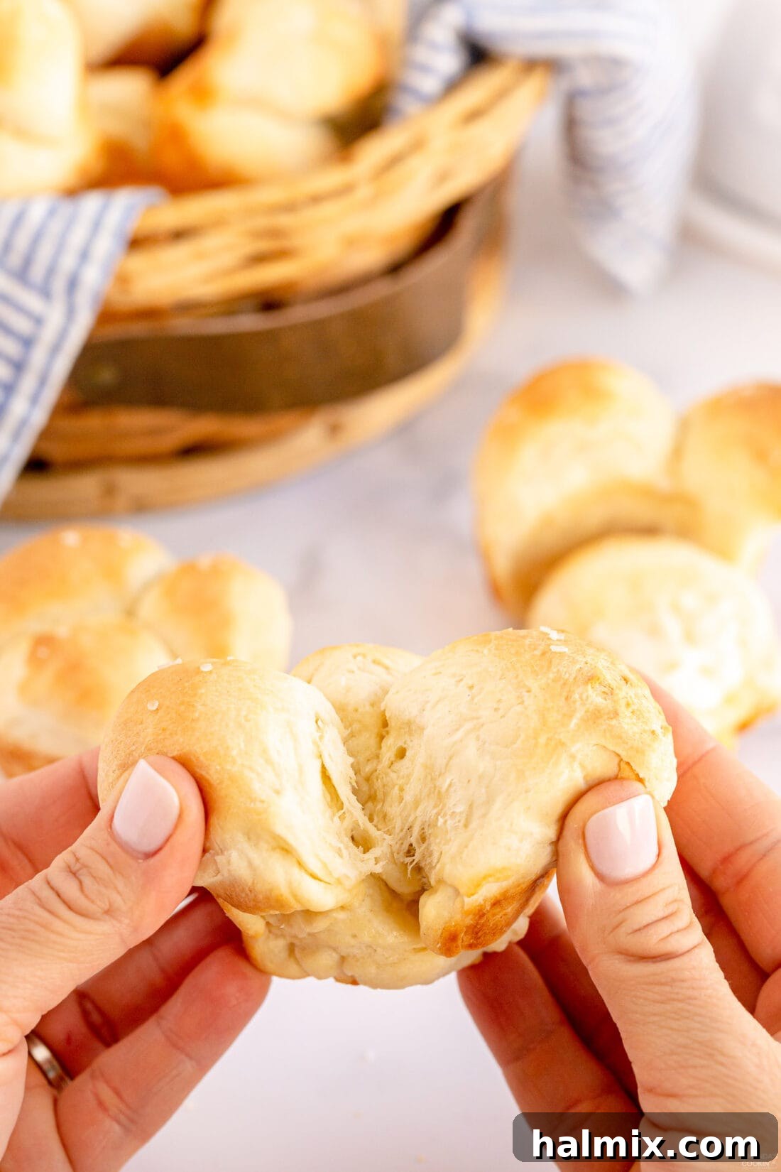 Hand separating a warm, soft Homemade Pull Apart Dinner Roll from the batch.