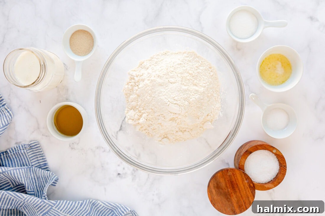 Array of ingredients laid out for making Homemade Pull Apart Dinner Rolls, including flour, yeast, milk, and olive oil.