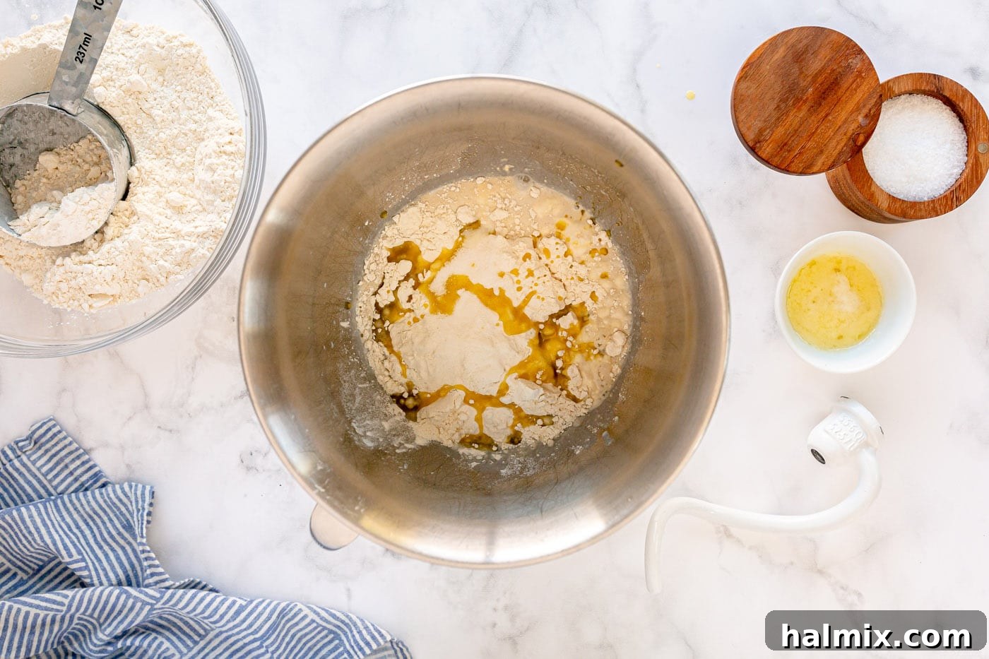 Activating yeast in a mixing bowl with warm milk and sugar.
