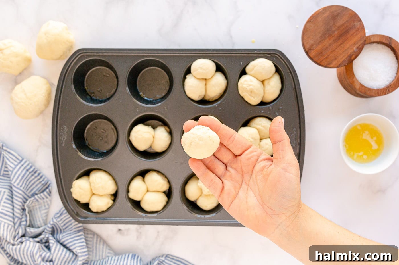 Small dough balls arranged in a muffin pan before baking.
