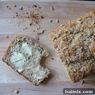 A close-up shot of a sliced sunflower whole wheat quick bread, revealing the texture and dispersed sunflower seeds, ready for various toppings.