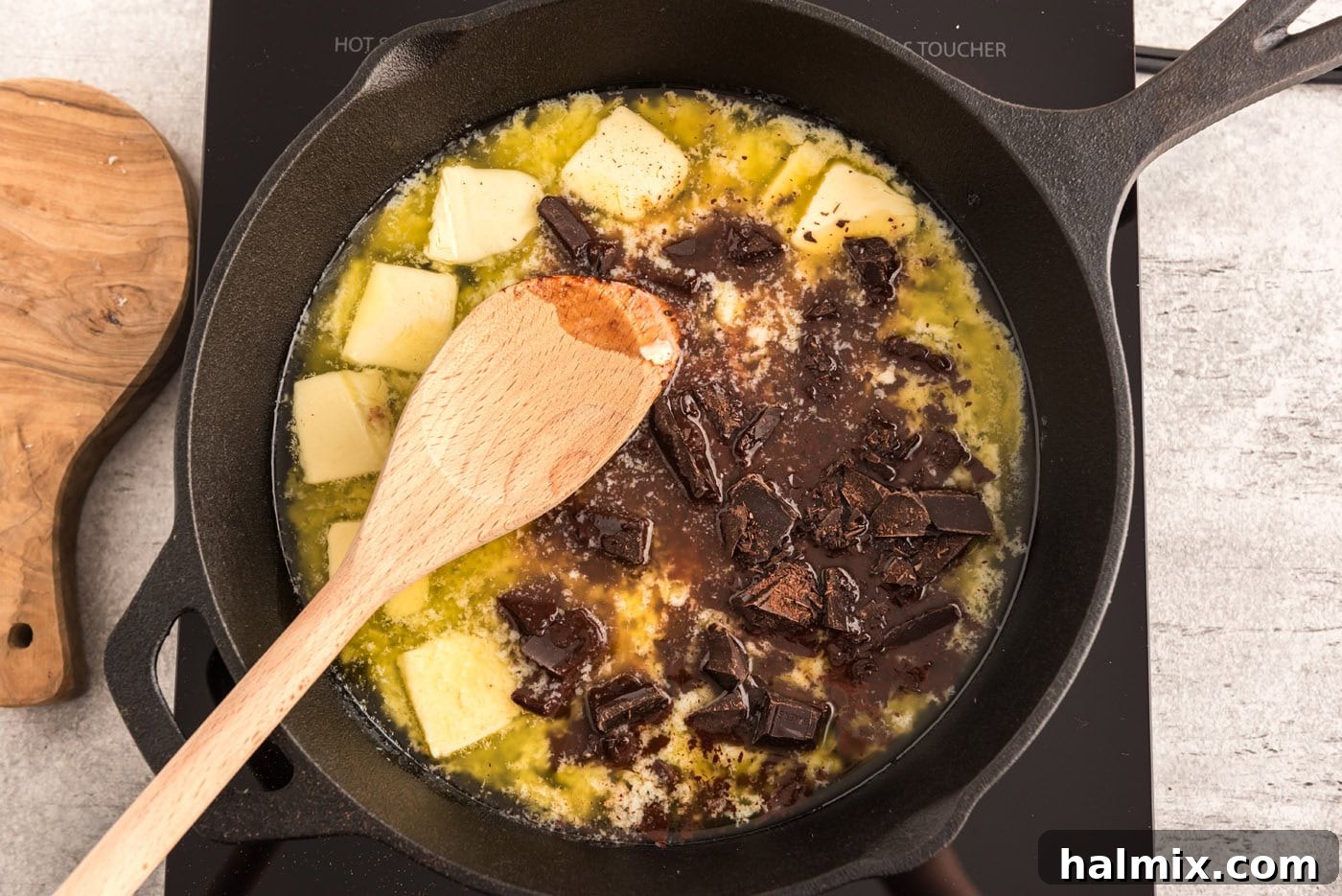 chopped chocolate and butter in a cast iron skillet with wooden spoon