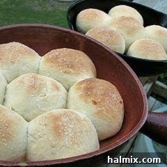 A close up photo of homemade dinner rolls in two cast iron skillets.