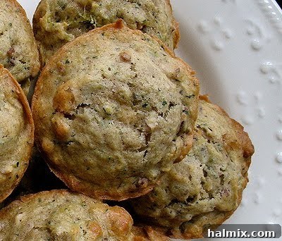 A close up overhead photo of a vanilla zucchini muffin with others in the background, showing off the perfectly baked top.