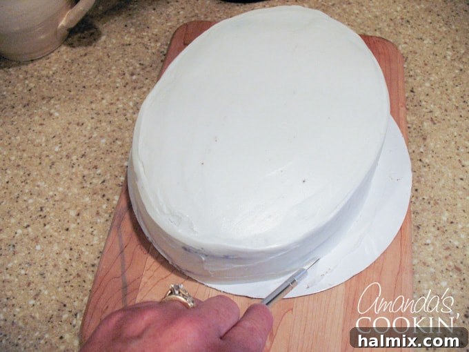 Spiderman Cake Power-Up: Homemade Marshmallow Fondant 3 A close up photo of a cake resting on cardboard that is being cut with an x-acto knife.