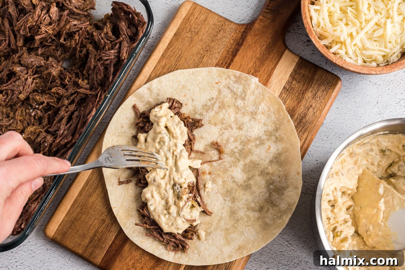 adding sour cream mixture to shredded beef enchiladas