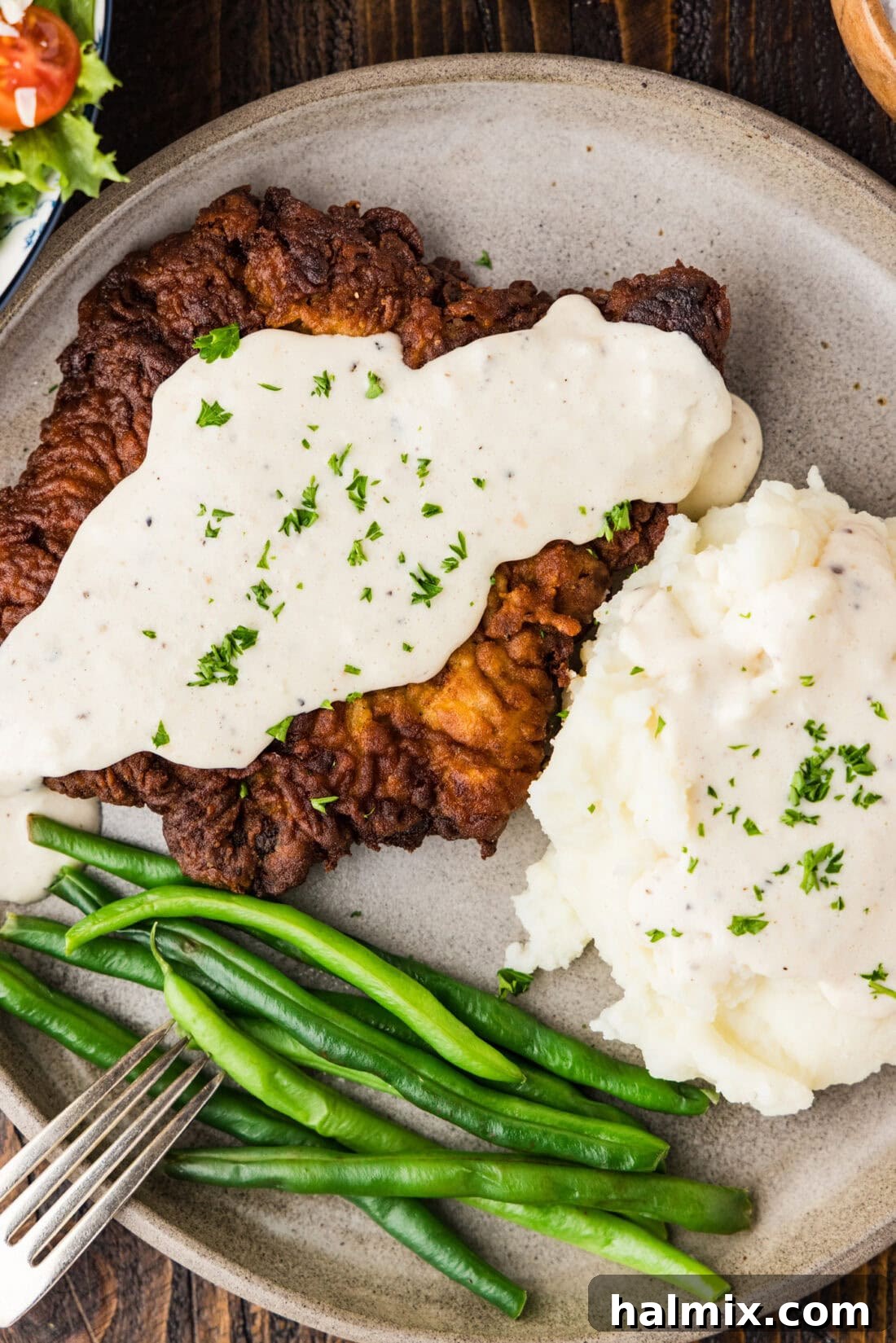 Close up photo of Chicken Fried Steak plated with mashed potatoes and green beans
