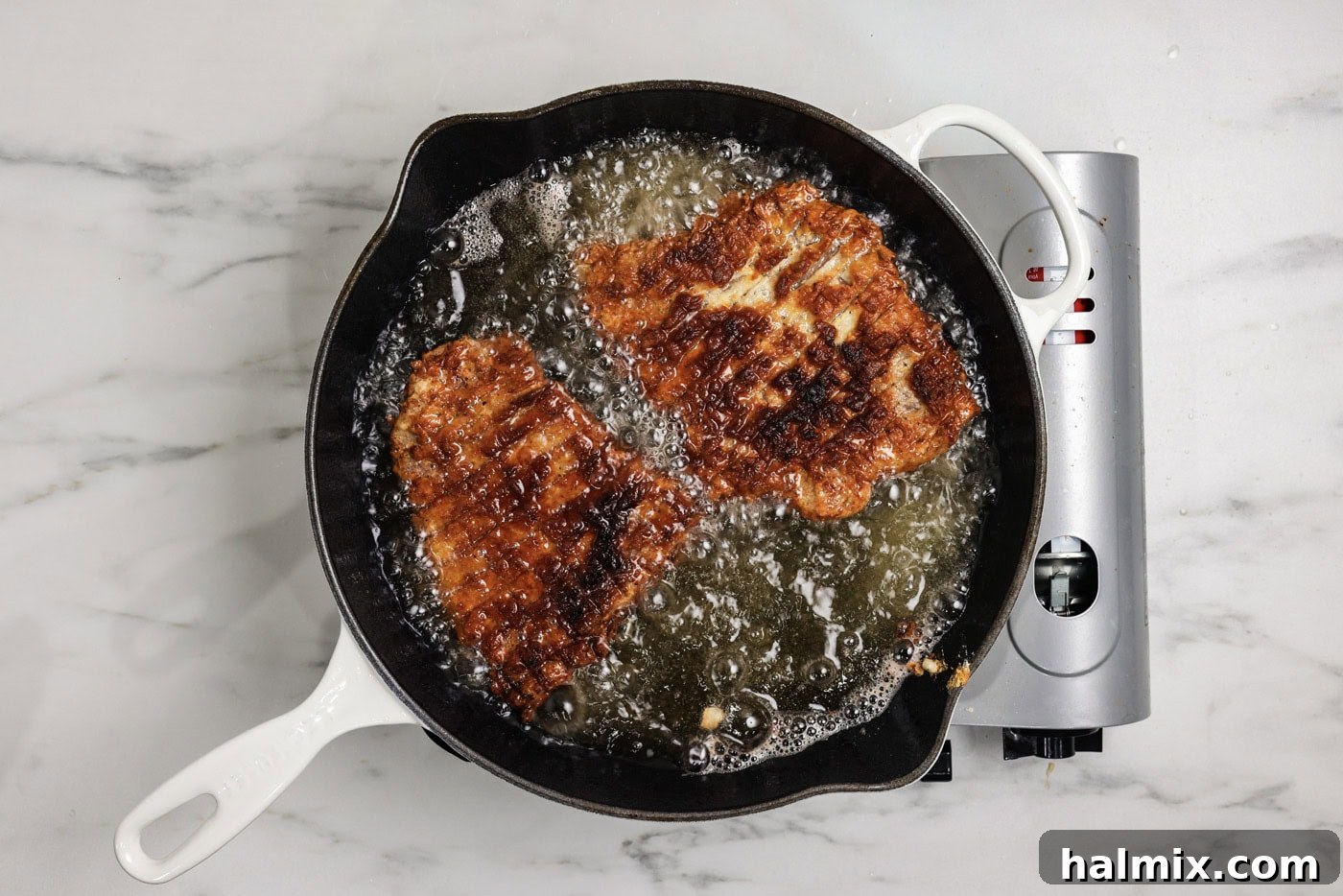 Chicken fried steak cooking in oil in a skillet
