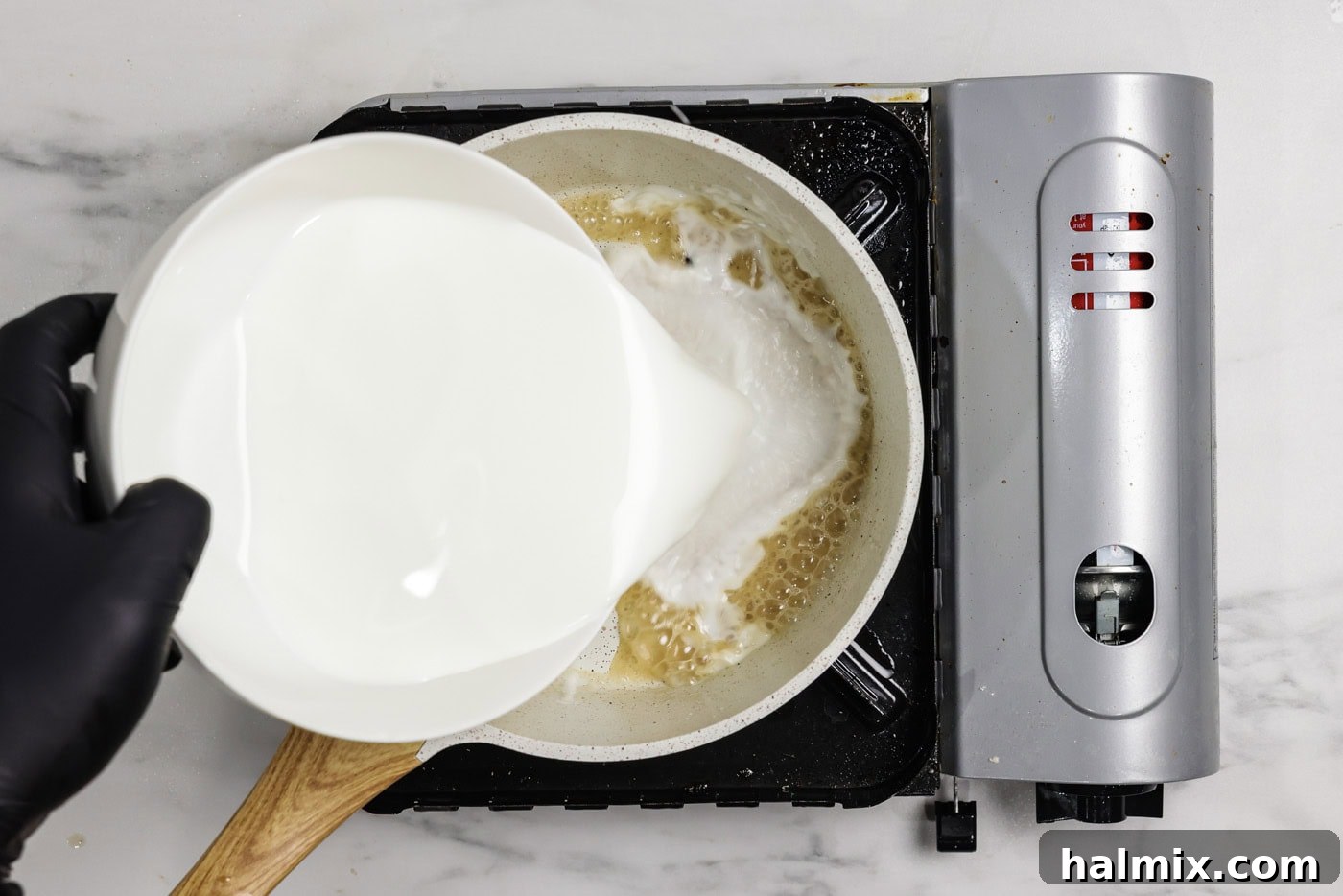 Milk being whisked into a roux in a saucepan
