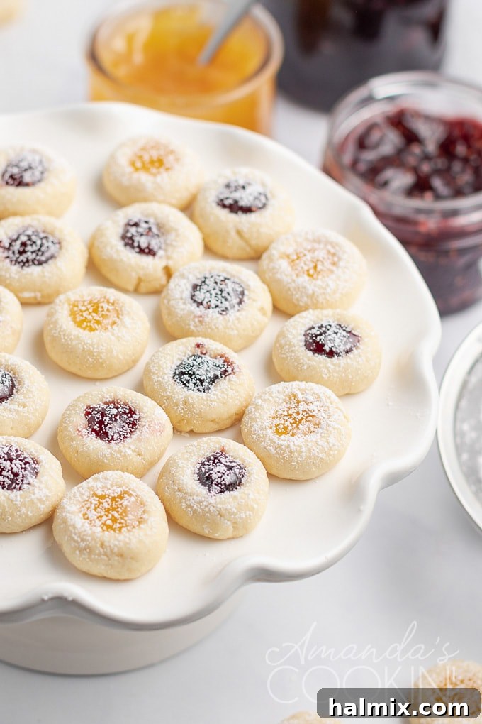A beautifully arranged plate of freshly baked thumbprint cookies, showcasing their golden edges and colorful jam centers, perfect for a holiday gathering.