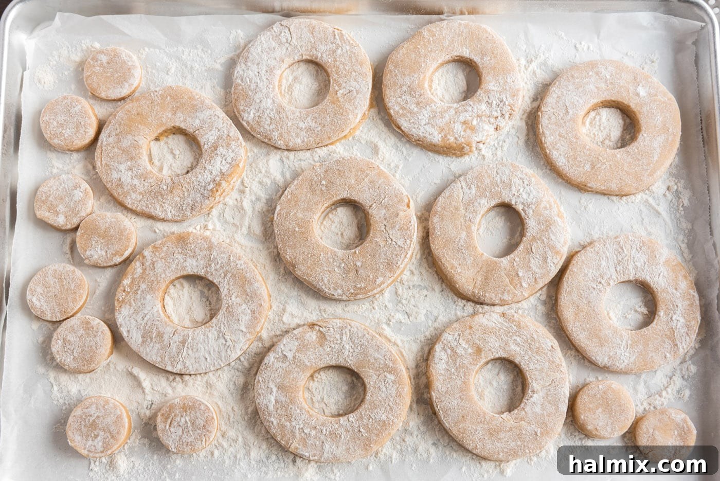 Neatly arranged donut shapes and doughnut holes on a baking sheet, ready for the fridge