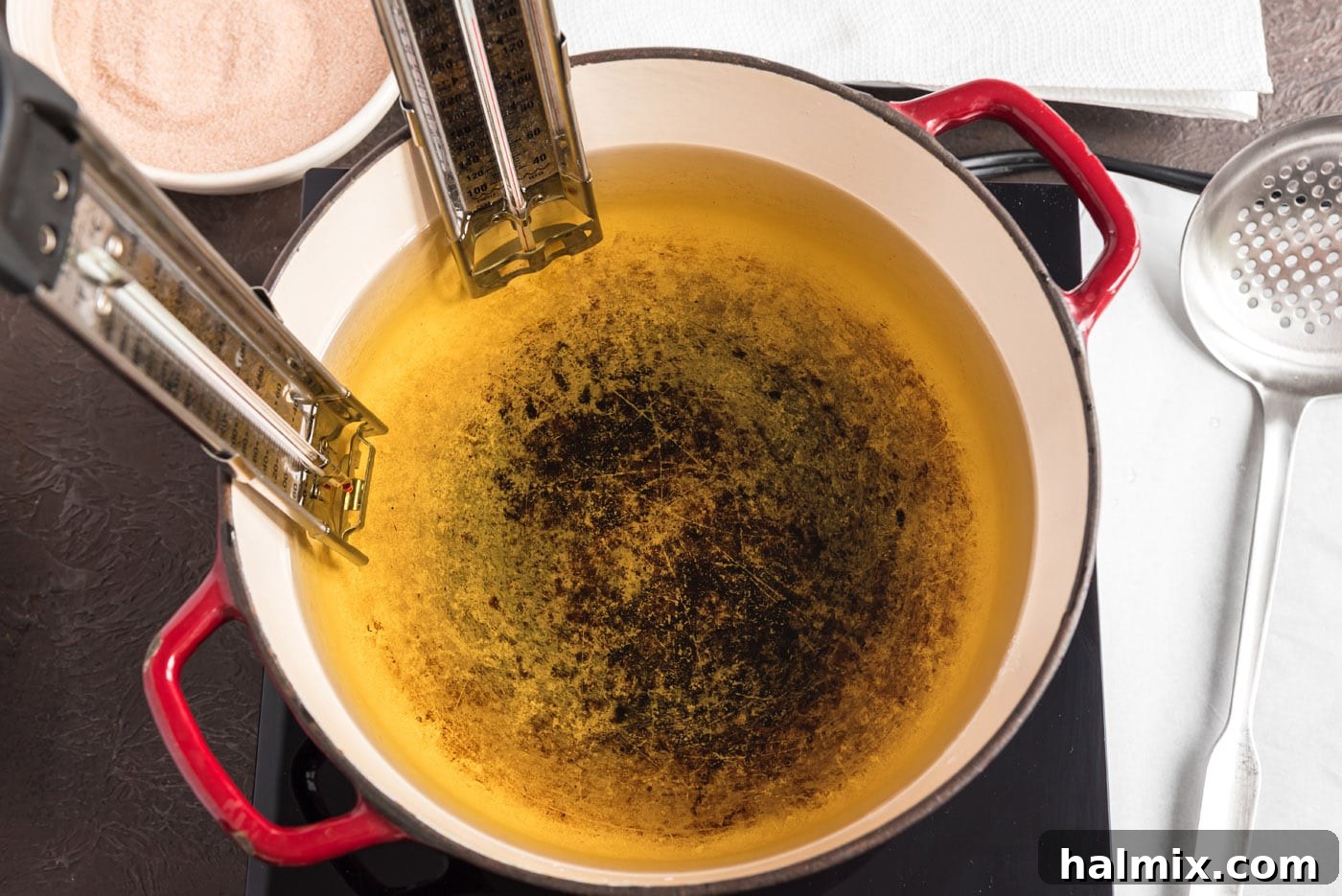 Oil heating in a saucepan with a candy thermometer attached, indicating correct temperature